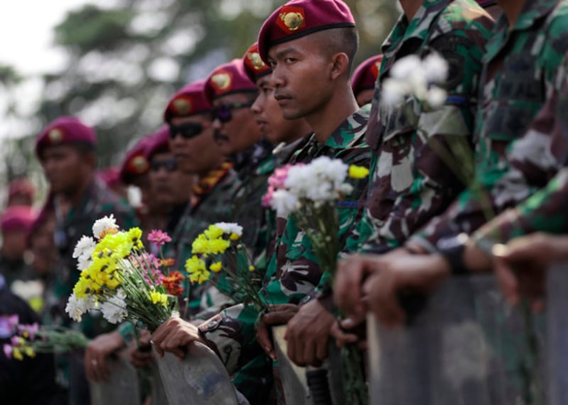 Indonesian marines hold flowers handed out by student protesters during a rally outside the parliament in Jakarta, Oct. 1, 2019. 