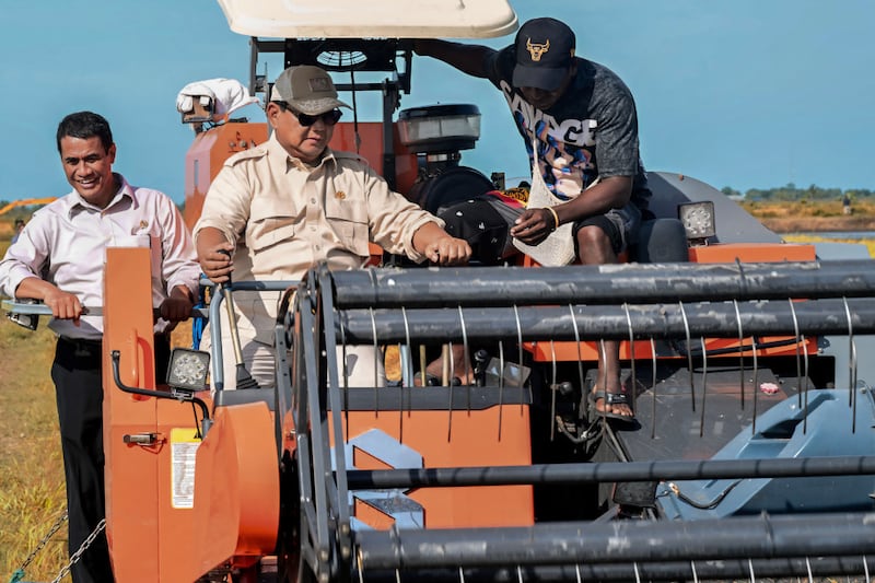 Presiden Prabowo Subianto (tengah) mengoperasikan mesin pemanen padi saat ia mengunjungi desa Telaga Sari di Merauke, provinsi Papua Selatan, sebagai bagian dari upayanya mendorong swasembada pangan nasional, 3 November 2024. [AFP/Istana Kepresidenan Indonesia]